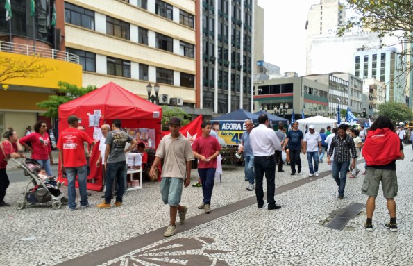 Curitibanos display their political affiliations before the October presidential elections. The red shirts are supporters of incumbent Dilma Rousseff and just behind them are the white tentsand banners of Aécio  Neves' fans.